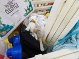 a basket full of baby clothes and toys in it
