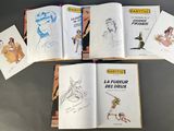six books of children ' s drawings are spread out on a table