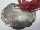 une vieille assiette en argent surmontée d'un cordon rouge
