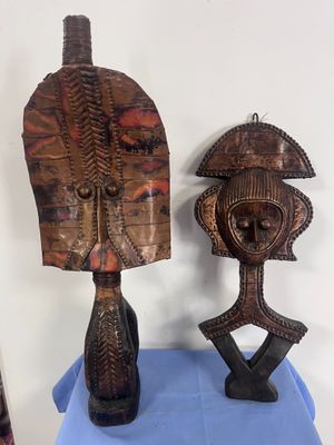 une paire de masques africains sculptés dans le bois, exposés sur une table bleue