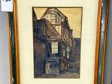 painting of a house in a frame on a shelf next to a vase
