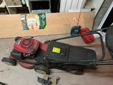 a red lawn mower sitting on the floor in a garage