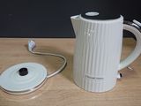 a white electric kettle sitting on a table next to a charger