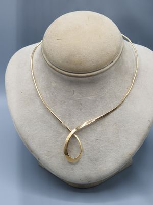 a white mannequin with a gold necklace on top of it