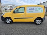 La camionnette jaune est garée sur le parking devant le bâtiment.
