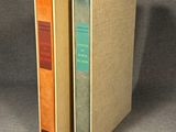 two books sitting on top of each other on a gray surface
