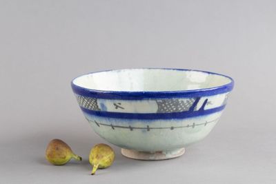 un bol bleu et blanc posé sur une table à côté d'une plante