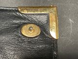 a black leather wallet with a gold button on it