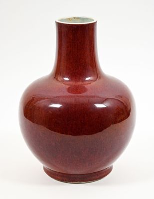 a red vase that is sitting on a white surface