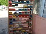 books are stacked on a rack in front of a pink building