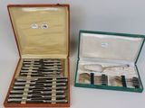 deux sets d'argenterie dans un coffret sur une table
