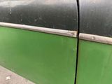 a close up of a green car door with a black handle