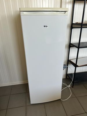 un réfrigérateur blanc dans un coin de la pièce, à côté d'une bibliothèque