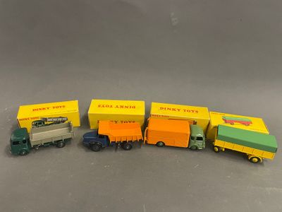 Quatre camions miniatures sont alignés en rang sur une table