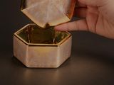 une personne tenant une bague en or dans une petite boîte