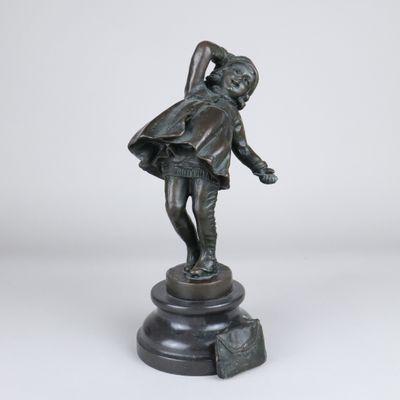 une statue en bronze représentant un garçon tenant un sac, posée sur un socle