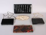 several purses are lined up on a white surface with a chain
