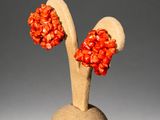 pair of red coral earrings on a wooden stand on a gray background