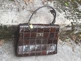 a brown purse sitting on the ground next to a stone wall