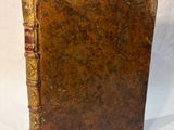 an old book sitting on top of a white cloth covered table