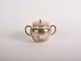 une théière ancienne en argent avec son couvercle, posée sur une surface blanche