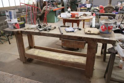 un établi au milieu d'un atelier, sur lequel sont posés des outils