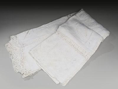 trois pièces de linge blanc ornées de dentelle, posées sur une table