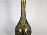 un vase en verre vert posé sur une surface blanche