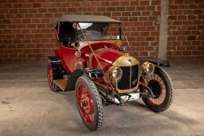 a red and gold car parked in front of a brick wall
