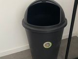 a black trash can next to a mirror on the floor