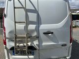 a white van parked in a parking lot with a ladder on the back