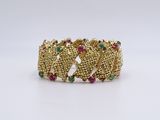 a close up of a gold bracelet with multi colored stones