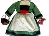 une poupée en peluche vêtue d'une robe verte et tenant un panier