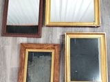 quatre miroirs encadrés sont posés les uns à côté des autres sur un plancher en bois