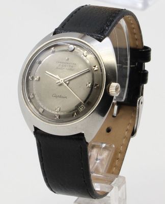 a silver watch with black leather strap on a clear stand