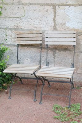 two wooden benches sitting next to each other in front of a stone wall