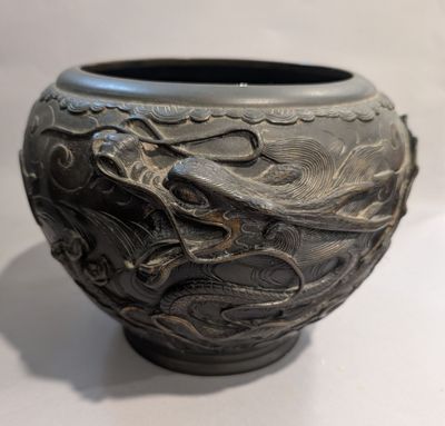 un vase noir orné d'un motif représentant un dragon
