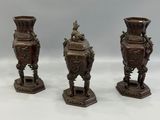 three antique bronze vases sitting on top of a white table
