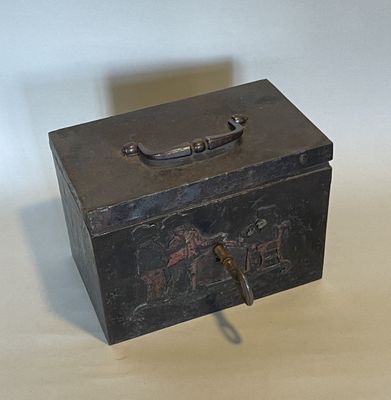 une petite boîte en métal munie d'une poignée, posée sur une table