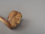 a pipe with a man ' s face on it next to a rock