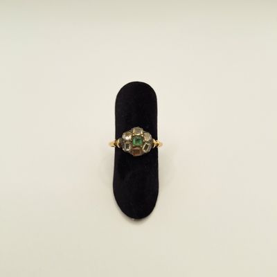 une bague en émeraude et diamants posée sur un présentoir en velours noir