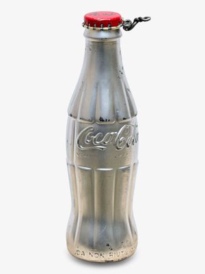 une bouteille de Coca-Cola argentée avec un bouchon rouge sur fond blanc