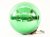 a green christmas ornament on a chain on a white surface