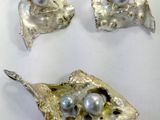 three pieces of silver and pearl jewelry sitting on a white surface