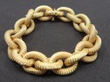 a close up of a gold chain bracelet on a black surface