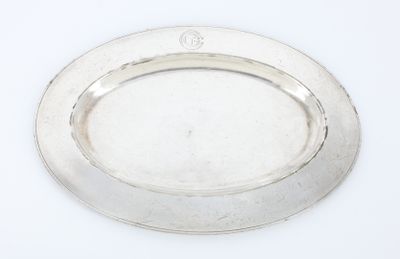 une assiette ovale en argent, avec un bord en argent sur une surface blanche