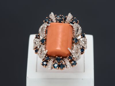 un gros plan d'une bague ornée d'une pierre orange entourée de diamants bleus et blancs