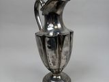 an antique silver plated pitcher with a handle on a stand