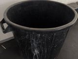 a black trash can sitting on the floor next to a white wall