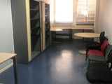 une pièce équipée d'un bureau, de chaises et d'un réfrigérateur